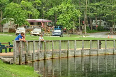 a woman and child looking over a wooden bridge over water at Sun Valley Campground Cottage 4 in Maple Grove Park