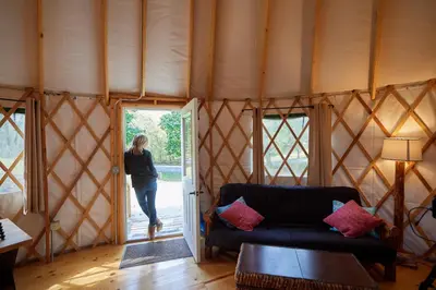 a woman walking into a room with a living room at Circle M Camping Resort Yurt in Lancaster