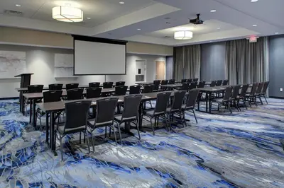 a conference room with tables and chairs and a screen at Fairfield Inn & Suites by Marriott Allentown West in Breinigsville