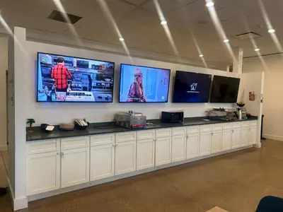 a counter with four televisions on a wall at Ramada by Wyndham Newark/Wilmington in Newark
