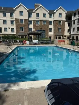 a large blue swimming pool in front of a building at Ramada by Wyndham Newark/Wilmington in Newark