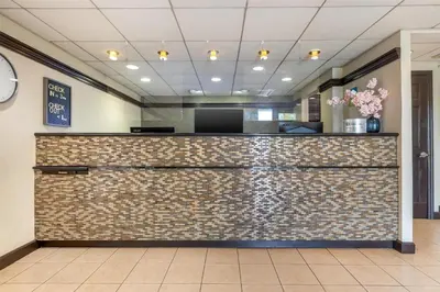a reception desk in a lobby with a brick wall at SureStay Hotel by Best Western East Brunswick in East Brunswick