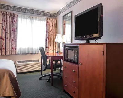 a hotel room with a television on a dresser with a desk at Quality Inn New Columbia-Lewisburg in New Columbia