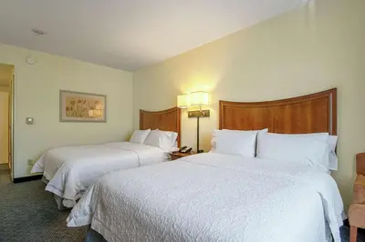 a hotel room with two beds and a chair at Hampton Inn Pine Grove in Pine Grove