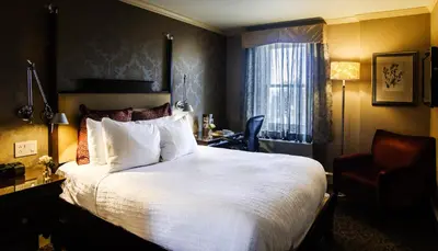 a hotel room with a large bed and a chair at Chestnut Hill Hotel in Philadelphia