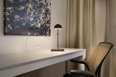 a desk with a lamp and a chair in a room at Hilton Garden Inn Newtown Square Radnor in Newtown Square