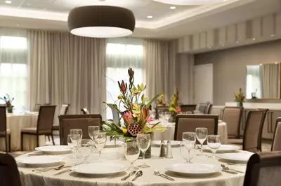 a dining room with a table with plates and glasses at Hilton Garden Inn Newtown Square Radnor in Newtown Square