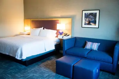 a hotel room with a bed and a blue couch at Hampton Inn & Suites Warrington Horsham in Warrington