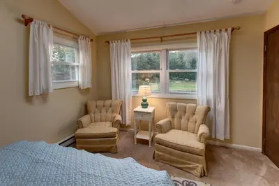 a bedroom with two chairs and a bed and windows at The Guest House in Margaretville