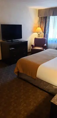 a hotel room with a bed and a tv and a chair at Heritage Hotel Lancaster in Lancaster