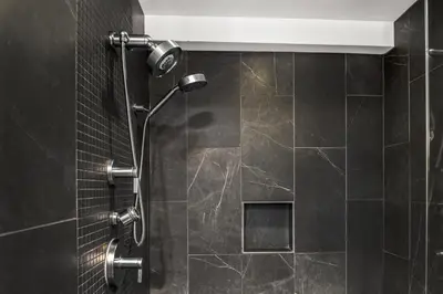 a bathroom with a shower with black tiles at Mount Airy Casino Resort - Adults Only 21 Plus in Mount Pocono