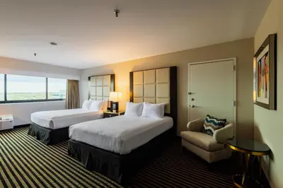 a hotel room with two beds and a chair at APA Hotel Woodbridge in Iselin