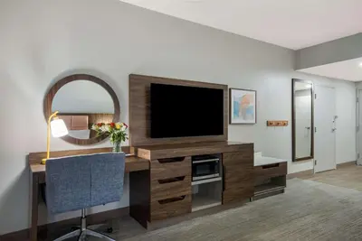 a living room with a television and a desk with a chair at Hampton Inn Linden in Linden