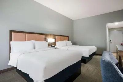 a hotel room with two beds and a chair at Hampton Inn Linden in Linden