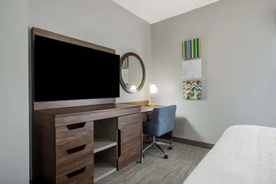 a bedroom with a desk with a tv and a bed at Hampton Inn Linden in Linden