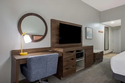 a bedroom with a desk with a tv and a mirror at Hampton Inn Linden in Linden
