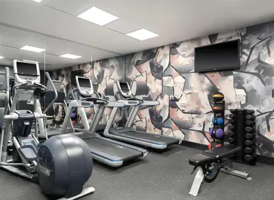 a gym with several tread machines and a mural at Hilton New York Fashion District in New York