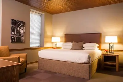 a bedroom with a bed with two lamps and a chair at Cork Factory Hotel in Lancaster