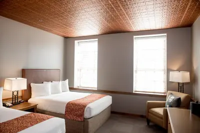 a hotel room with two beds and a chair and two windows at Cork Factory Hotel in Lancaster