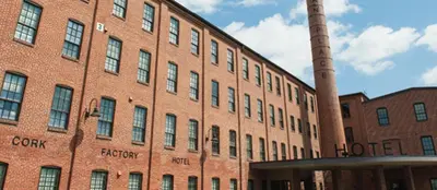 a large brick building with a chimney and a pole at Cork Factory Hotel in Lancaster