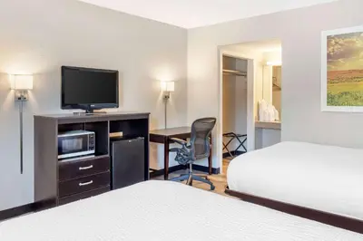 a hotel room with two beds and a desk with a television at Days Inn by Wyndham Wrightstown McGuire AFB Bordentown in Wrightstown