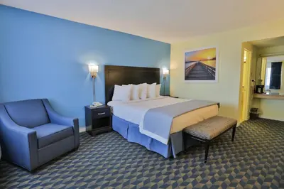 a hotel room with a large bed and a chair at Days Inn by Wyndham Wrightstown McGuire AFB Bordentown in Wrightstown