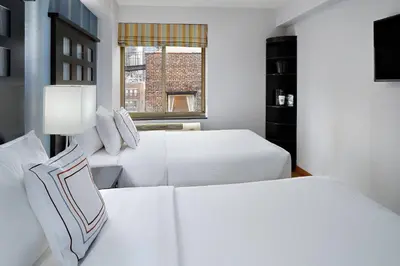 a white bedroom with two beds and a window at Fairfield Inn & Suites by Marriott New York Manhattan/Chelsea in New York