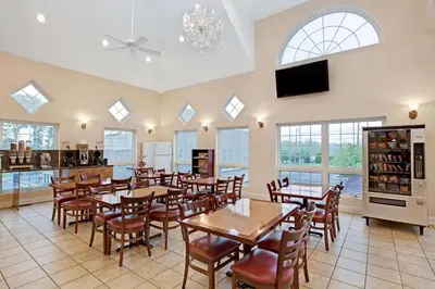 a dining room with tables and chairs and windows at Howard Johnson by Wyndham Blackwood Near Philadelphia in Blackwood