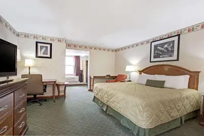 a hotel room with a bed and a desk at Ramada by Wyndham Flemington in Flemington