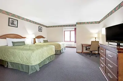 a hotel room with two beds and a flat screen tv at Ramada by Wyndham Flemington in Flemington