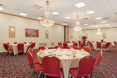 a conference room with tables and chairs and chandeliers at Ramada by Wyndham Flemington in Flemington