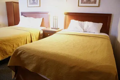 two beds in a hotel room with yellow sheets at Raritan Hotel in Edison