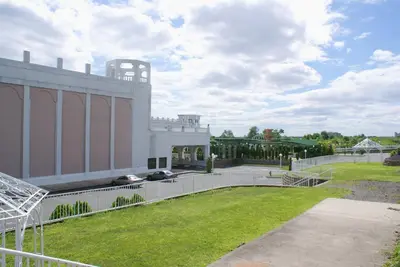 a large white building with a grassy yard at Raritan Hotel in Edison
