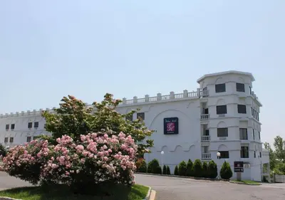 a white building with a flowering tree in front of it at Raritan Hotel in Edison