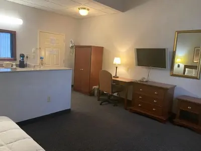 a hotel room with a bed and a desk with a television at Raritan Hotel in Edison