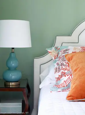 a bed with a blue lamp on a nightstand with a pillow at Stagecoach Inn in Goshen