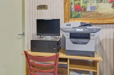 a computer and printer on a desk with a chair at TraveIodge by Wyndham Parsippany in Parsippany