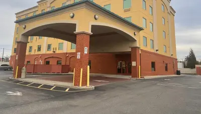 a large yellow building with an arch in a parking lot at Spark by Hilton Rahway in Rahway