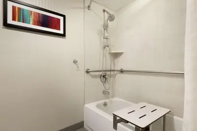 a white bathroom with a shower and a toilet at Embassy Suites by Hilton Piscataway Somerset in Piscataway