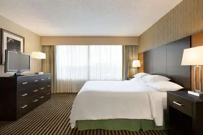 a hotel room with a large bed and a television at Embassy Suites by Hilton Piscataway Somerset in Piscataway