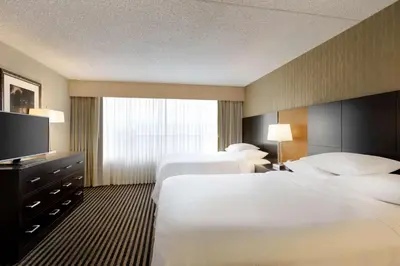 a hotel room with two beds and a flat screen tv at Embassy Suites by Hilton Piscataway Somerset in Piscataway