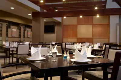 a dining room with tables with napkins and wine glasses at Embassy Suites by Hilton Piscataway Somerset in Piscataway