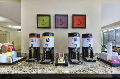a group of four coffee machines on a counter at Hampton Inn Clinton in Clinton