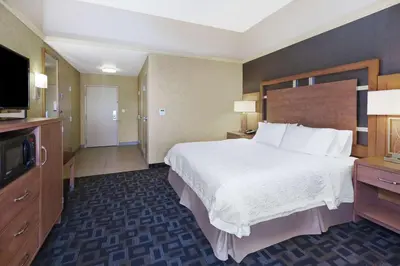a hotel room with a bed and a flat screen tv at Hampton Inn Clinton in Clinton