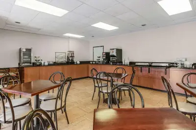 a restaurant with tables and chairs and a kitchen at SureStay Plus Hotel by Best Western McGuire AFB Jackson in Cookstown