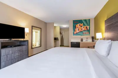 a large bedroom with a large bed and a flat screen tv at SureStay Plus Hotel by Best Western McGuire AFB Jackson in Cookstown