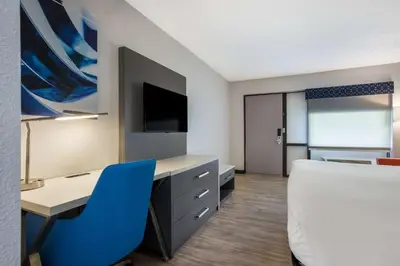 a room with a bed and a desk and a blue chair at Best Western Bordentown Inn in Bordentown