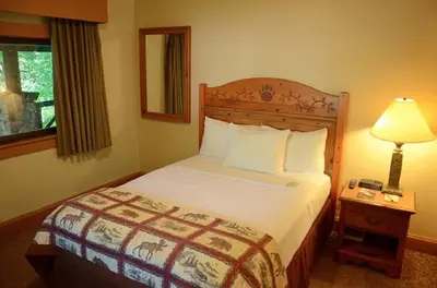 a bedroom with a bed and a lamp and a window at Overlook Lodge and Stone Cottages at Bear Mountain in Highland Falls