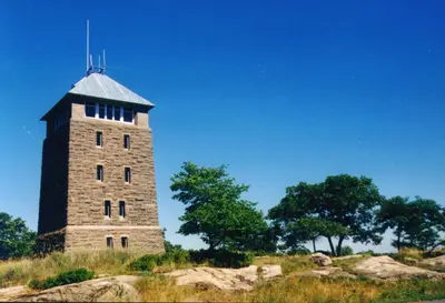 a brick tower on top of a hill with trees at Overlook Lodge and Stone Cottages at Bear Mountain in Highland Falls
