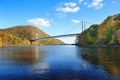 a bridge over a river with a bridge in the background at Overlook Lodge and Stone Cottages at Bear Mountain in Highland Falls